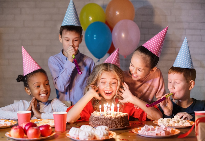 Enfants qui regardent un gâteau d'anniversaire avec des chandelles